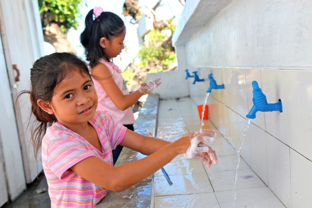 February 2014, Santo nino primary school in Baranggay santo nino, Tanauan town. The school re-opened on January 6th almost 2 months after the events of November 8th, it was badly damaged and the the classrooms are all roofless and most of the furniture was damaged, most children go to school carrying their own chairs from home. UNICEF provided tents, school supplies, latrines and hand washing facilities and supported teacher's training. In the image Venus Mueva 8 grade 2 washes her hands after using the latrines. Venus lost her younger sister Viana 4 years old and she lives with her parents a few meters away from the school in a temporary shelter, their house was washed away on November 8th. UNICEF SUPPORTED THE REHABILITATION OF LATRINES AND NEW HAND WASHING FACILITY. VENUS MUEVA IS 8 YEARS OLD AND SHE LIVES WITH HER PARENTS JUST A FEW METERS AWAY FROM THE SCHOOL IN A TEMPORARY SHELTER. HER HOUSE WAS WASHED AWAY AND HER YOUNGER SISTER VIANA DIED, SHE WAS ONLY 4 YEARS OLD